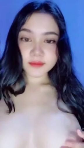 Asian woman with black hair shows off her curves in a purple bra and bronze make
