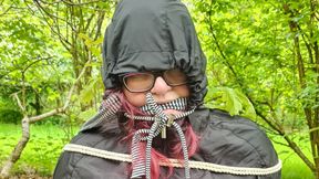 Struggling woman tied to tree in a raincoat